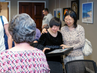 Annie Fan, center, was one of many to answer the cal this year at the Hillsdale Access For All Fifth Annual Art Show For People With Disabilities. The reception was May 1 at Hillsdale Free Public Library, where the exhibition will run throughout May. John Snyder photo.