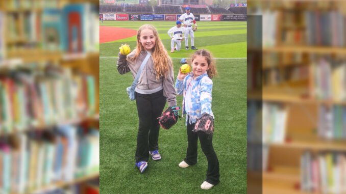 Now pitching for the New York Boulders… Berkeley school sisters Scarlett Hlavaty, a fourth grader, and Madelyn Hlavaty, a first grader, throw out a ceremonial first pitch during the “Rockland Boulders Reading Challenge” celebration at Clover Stadium as their father, Kevin Hlavaty, prepares to catch both balls at once. Courtesy photo