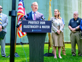 Rep. Josh Gottheimer (D-5) speaks Aug. 12 in Park Ridge, with one of the borough’s massive water tanks as a backdrop. Joining him are, among others, state Sen. Holly Schepisi (R-39), New Jersey Cybersecurity and Communications Integration Cell Director Michael Geraghty, Bergen County Prosecutor Mark Musella, Bergen County Chief of Detectives Jeff Angermeyer, Mayor Keith Misciagna, and councilmen Will Fenwick and Bruce Goldsmith. John Snyder photo.