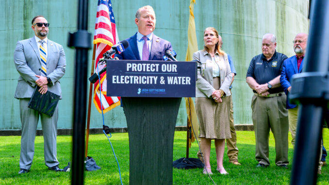 Rep. Josh Gottheimer (D-5) speaks Aug. 12 in Park Ridge, with one of the borough’s massive water tanks as a backdrop. Joining him are, among others, state Sen. Holly Schepisi (R-39), New Jersey Cybersecurity and Communications Integration Cell Director Michael Geraghty, Bergen County Prosecutor Mark Musella, Bergen County Chief of Detectives Jeff Angermeyer, Mayor Keith Misciagna, and councilmen Will Fenwick and Bruce Goldsmith. John Snyder photo.